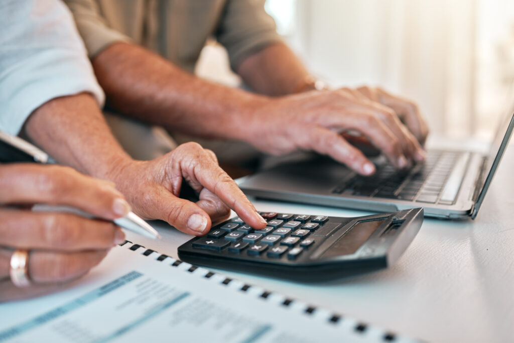 Hands, laptop and calculator for a home budget, planning retirement or online payment for banking. Accounting, couple or people with financial research, mortgage or analysis of tax paperwork.